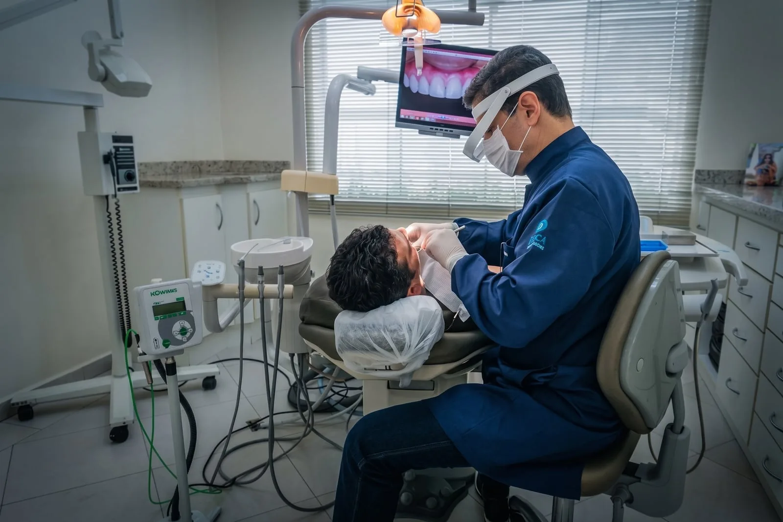 Dr. Eduardo Martins durante atendimento, com imagem intraoral exibida no monitor