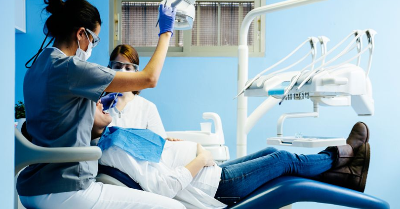 Dentista avaliando paciente grávida em consultório odontológico