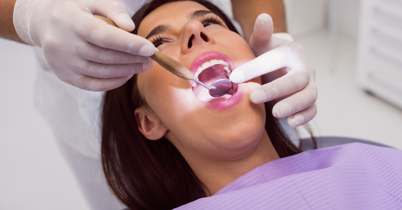 Paciente mulher sendo examinada por dentista